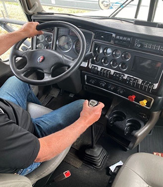 Interior of semi truck with driver holding wheel and gears