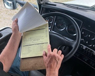 Licensing trainer reviewing driving checklist inside semi truck